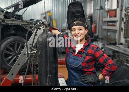 Cheerful woman auto mechanic standing in vehicle repair shop Stock Photo