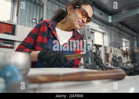 Female auto mechanic using hammer in automobile garage Stock Photo