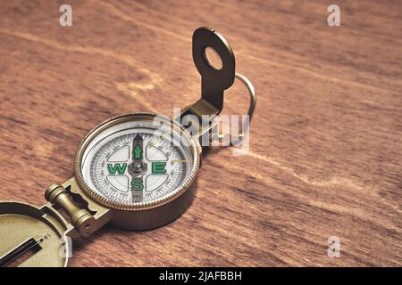 A simple dry magnetic portable compass. Compass on a wooden table. Navigation device Stock Photo
