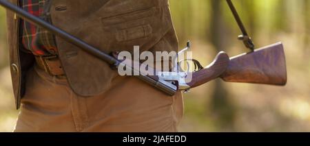 Close-up of hunter man carrying his rifle gun in forest. Stock Photo