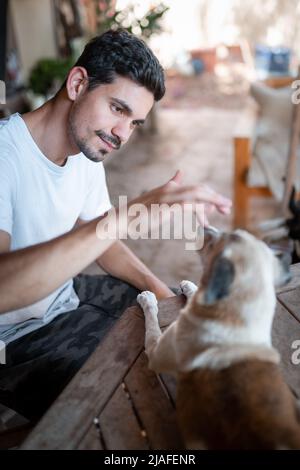 vertical composition. Young man interacts with a dog in the garden Stock Photo