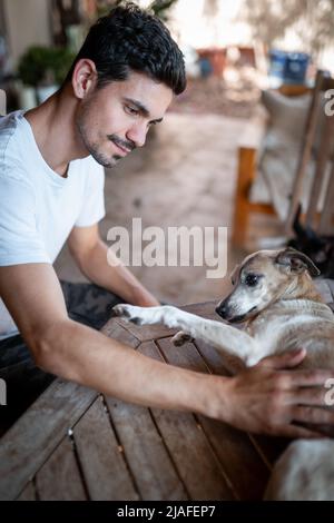 vertical composition. Young man interacts with a dog in the garden Stock Photo