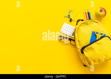 Yellow school backpack with colorful school stationery Stock Photo