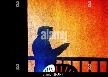DOBBELGANGER:A man's shadow separates from self inverted in time and consciousness for a selfie of a balcony view sunrise. Stock Photo