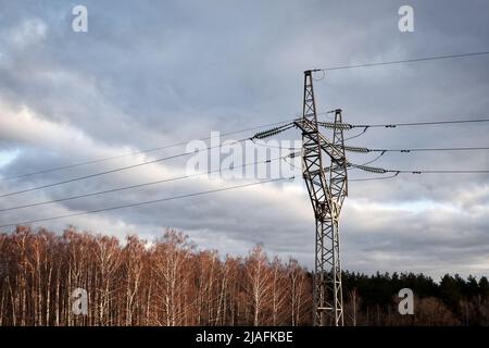 High voltage line against the sky. Electricity transmission pylon silhouetted against sunset sky Stock Photo