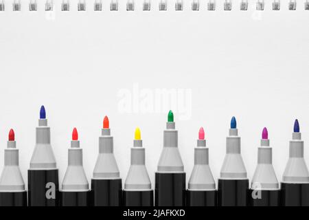 Sketching markers for drawing. Professional markers for artists in different shades of colours.  White paper sheet of sketchbook on background. Stock Photo