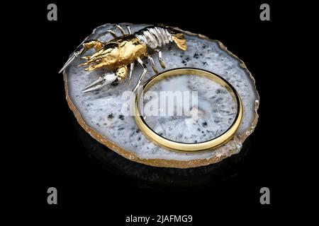 Gilded luxury crystal caviar bowl on stand made of natural quartz, carved brass fish crawfish figurine on a black background. Stock Photo