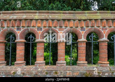 Ornamental curved brick wall with arches and columns and wrought iron Stock Photo