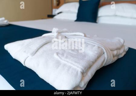 Close-up of a folded white terry robe on the bed Stock Photo