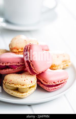 Heart shaped Sweet macarons on plate on a white table. Stock Photo