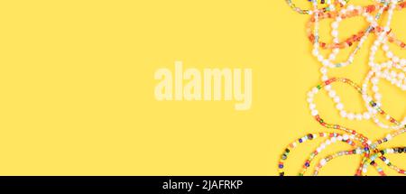 Banner with necklaces and bracelets made from beads and pearls on a yellow background with copyspace. Stock Photo