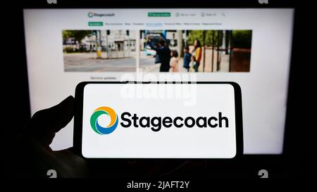 Person holding cellphone with logo of British bus company Stagecoach Group plc on screen in front of business webpage. Focus on phone display. Stock Photo