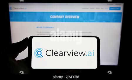 Person holding smartphone with logo of facial recognition company Clearview AI Inc. on screen in front of website. Focus on phone display. Stock Photo