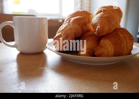 Croissants and a cup on the table in front of the window Stock Photo