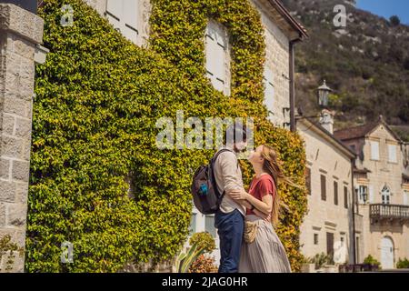 Happy couple in love man and woman tourists enjoying Colorful street in Old town of Perast on a sunny day, Montenegro. Travel to Montenegro concept Stock Photo