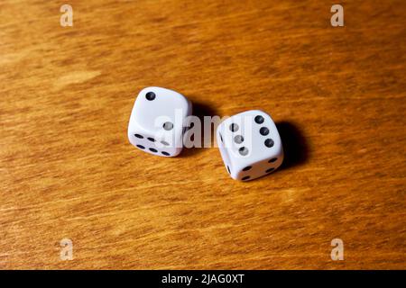 Two white dice on a wooden table Stock Photo