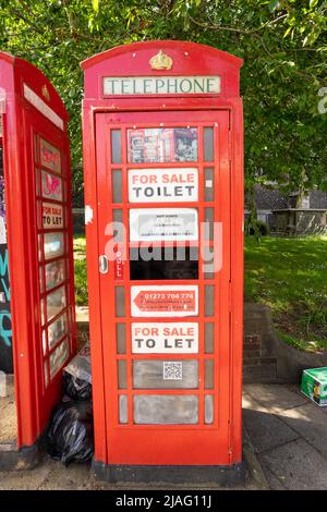 Traditional red telephone box being used with signs on glass stating toilet for sale Stock Photo