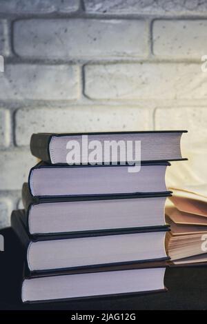 Stack of books close-up on wooden table against wall background Stock Photo