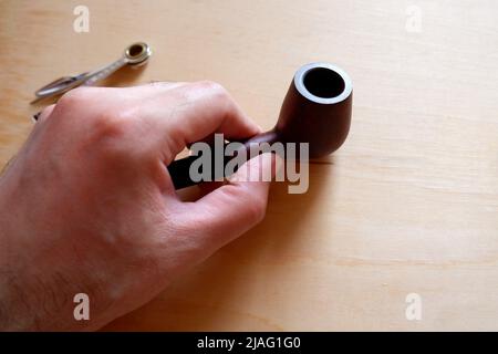 Man's hand takes a smoking pipe Stock Photo