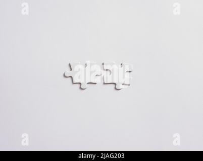 Two blank or empty jigsaw puzzle pieces is about to connect on white background. Stock Photo