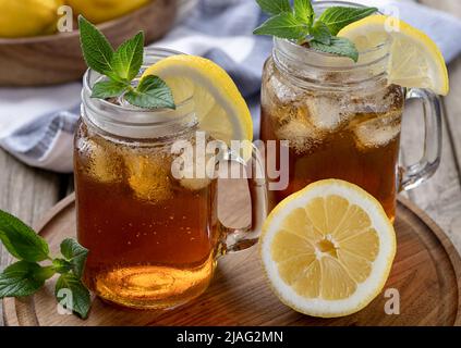 Two glasses of ice tea with lemon slice and mint on a wooden tray Stock Photo