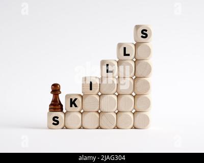 To develop personal, social or technical skills concept. Chess pawn is climbing the ladder of wooden cubes with the word skills. Stock Photo