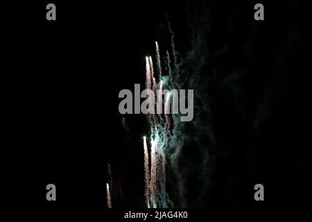 Flying up, bright volleys of fireworks, white, against the background of white haze and the night sky. High quality photo Stock Photo