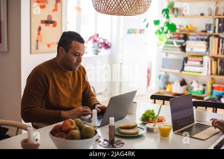 Male freelancer using laptop while working from home Stock Photo