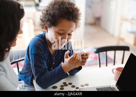 Happy boy looking at credit card while sitting with mother at home Stock Photo