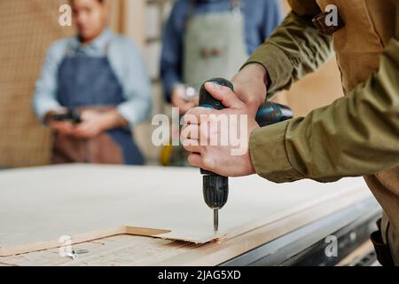 Close up of male carpenter drilling wood while building handmade furniture in workshop, copy space Stock Photo