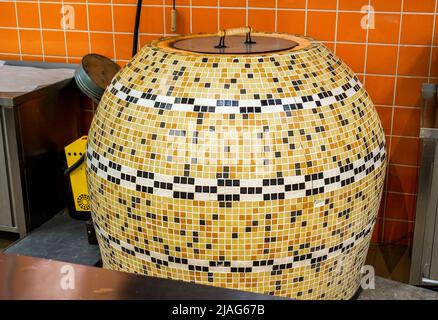 Large tandoor oven for making flat unleavened white bread in the form of a thin flatbread made of wheat flour. The furnace is in the shop Stock Photo