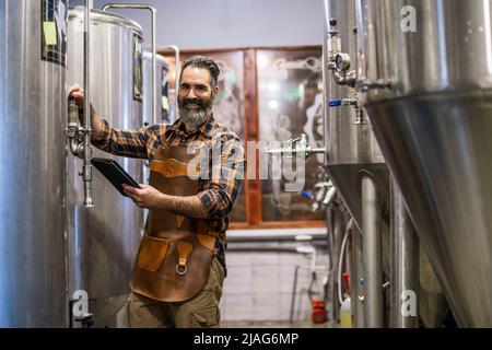 Man is working at craft beer factory. He is operating machinery in brewery. Small family business, production of craft beer. Stock Photo