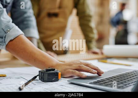 Close up of female worker using laptop while discussing production plans in workshop, copy space Stock Photo