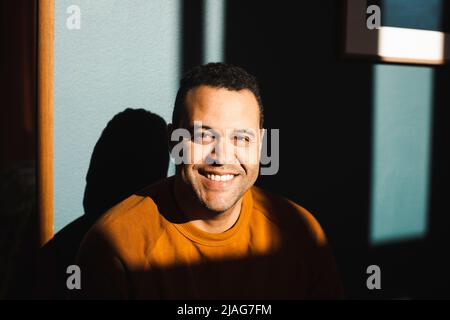 Portrait of smiling man enjoying sunlight at home Stock Photo