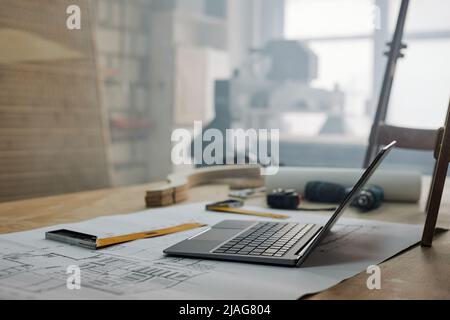 Close up background image of opened laptop on table in hazy carpenters workshop, copy space Stock Photo