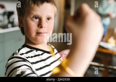 Thoughtful boy with down syndrome at home Stock Photo