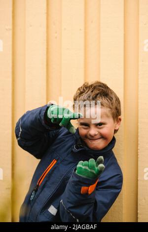 Portrait of smiling boy with disability making finger frame gesture against wall Stock Photo