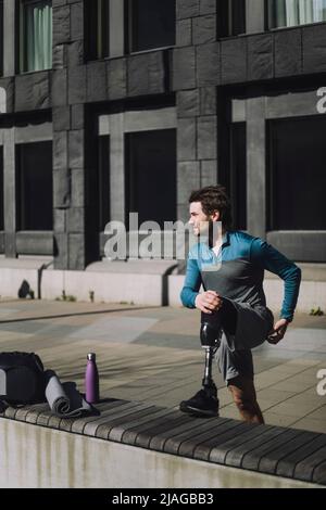 Full length of young man with disability doing stretching exercise Stock Photo