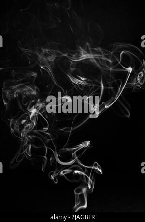 Black and white swirling, ascending smoke pattern on a black background, photo could be used as a background, smoke texture or abstract, or general st Stock Photo