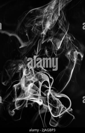 A white, swirling, ascending smoke pattern on a black background, photo could be used as a background, smoke texture or abstract, or general stock pho Stock Photo