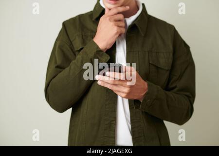 Cropped image of pensive man rubbing chin when deciding what to reply on text message Stock Photo