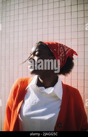Smiling woman wearing bandana standing with eyes closed during sunny day Stock Photo