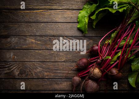 Fresh red beetroot with herbage green leaves over wooden background, top view Stock Photo