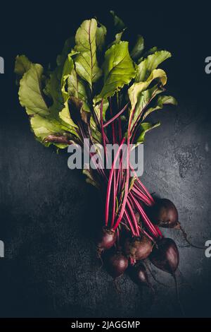 Fresh red beetroot with herbage green leaves over black background, top view Stock Photo