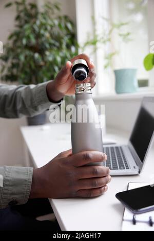 Close Up Of Thirsty Man In Office Opening Reusable Water Bottle For Drink Stock Photo