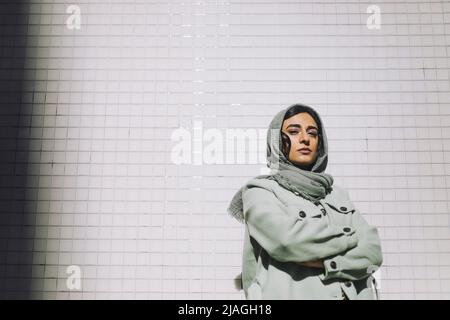 Portrait of confident woman standing with arms crossed against wall Stock Photo