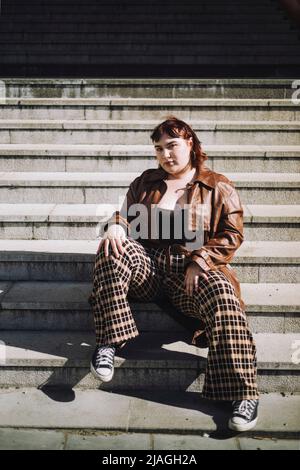 Portrait of confident young woman sitting on steps during sunny day Stock Photo