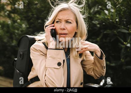 Blond businesswoman contemplating while talking on smart phone Stock Photo