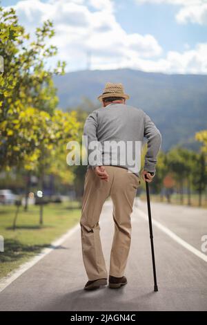 Senior man walking with a cane on an asphalt pedestrian lane Stock Photo