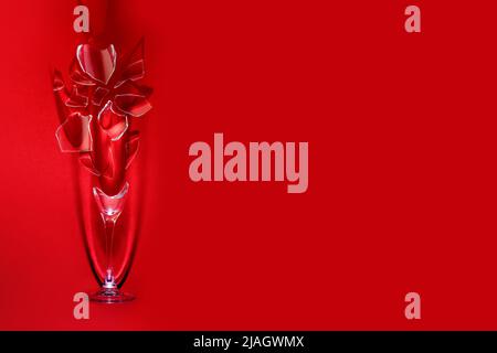 A wine glass shattered into small fragments, as a symbol of a quarrel, an accident, a rupture, on a bright red background. Stock Photo